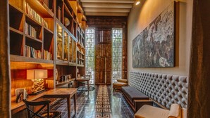 Un coin lecture confortable avec des étagères à livres, un banc rembourré et un grand tableau accroché au mur.