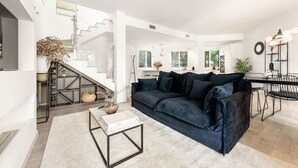 Ein modernes Wohnzimmer mit einem dunkelblauen Sofa, einem weißen Couchtisch und einer Treppe, die zu einer oberen Etage führt.