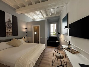 Een moderne hotelkamer met een groot bed, een bureau met een laptop, een stoel en een tafeltje met een fles en glazen.