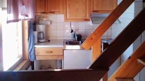 Una cocina compacta con armarios de madera, una cafetera y un lavamanos.