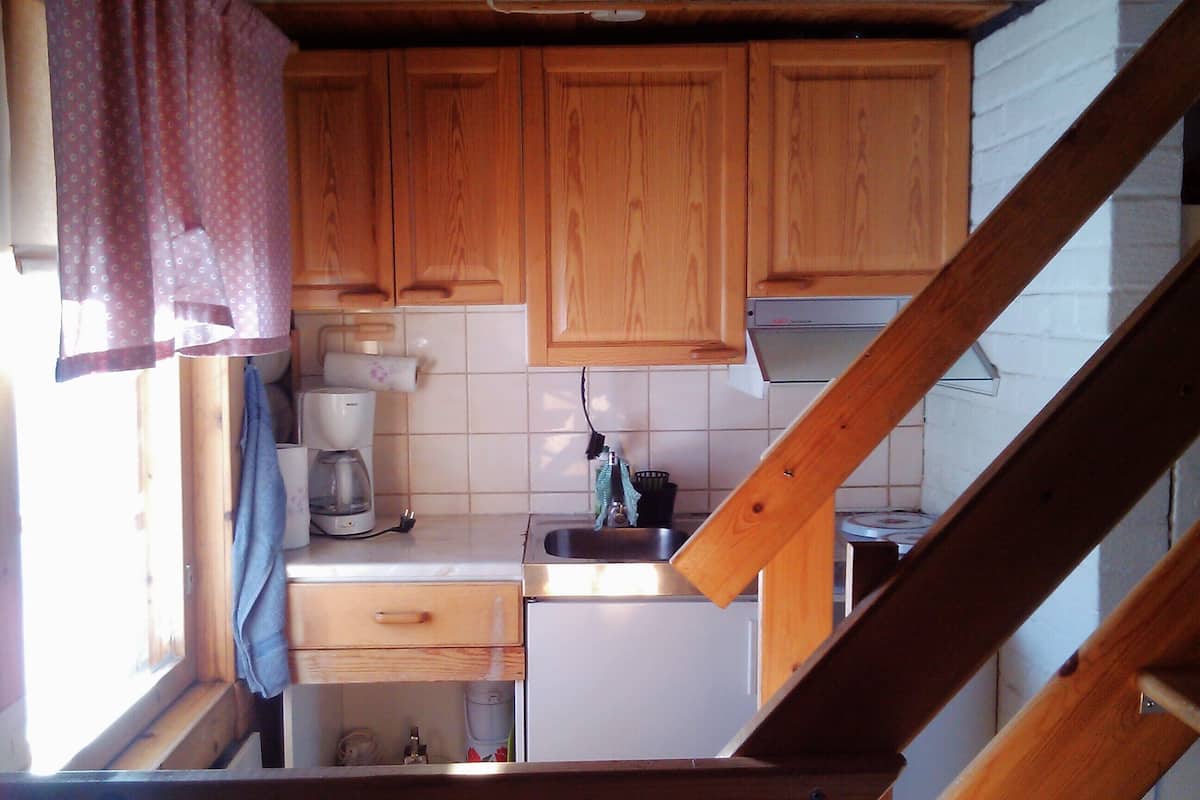 A compact kitchen with wooden cabinets, a coffee maker, and a sink.