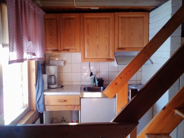 Una cucina compatta con mobili in legno, una macchina per il caffè e un lavandino.