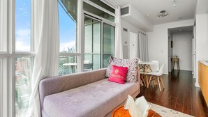 A modern living room with a sofa, a coffee table, and a view of the city through large windows. - GLOBALSTAY. Panoramic 1 Bedroom Condo in Downtown (Toronto/Canada)