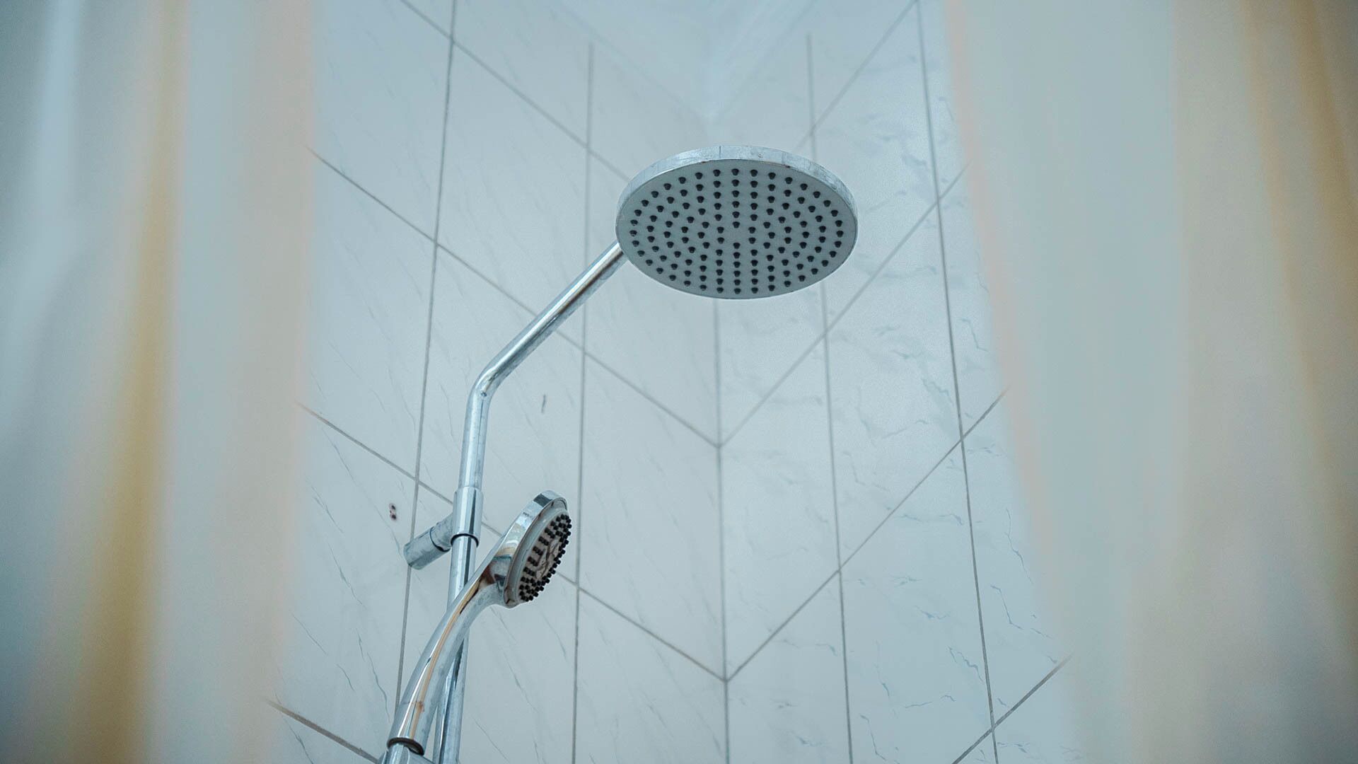 A shower with a handheld showerhead and a fixed overhead showerhead.