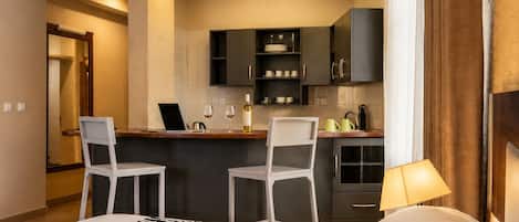 Une chambre d’hôtel comprenant un lit, un bureau avec deux chaises, une kitchenette et une salle de bain.
