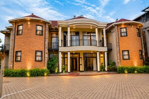 A multi-story hotel with a central entrance, balconies, and a paved driveway. - QUALITY INN HOTEL KIGALI (Kigali)