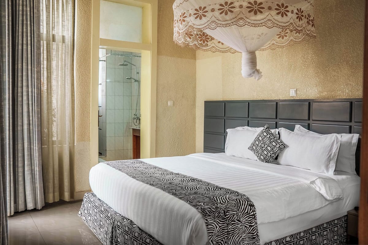 Una habitación de hotel con una cama grande, ducha y un aplique decorativo en el techo.