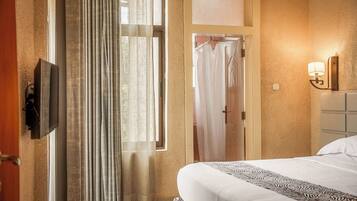 Hotelkamer met een bed, een aan de muur bevestigde televisie, een douchegedeelte en een badkamer met een handdoekhouder.