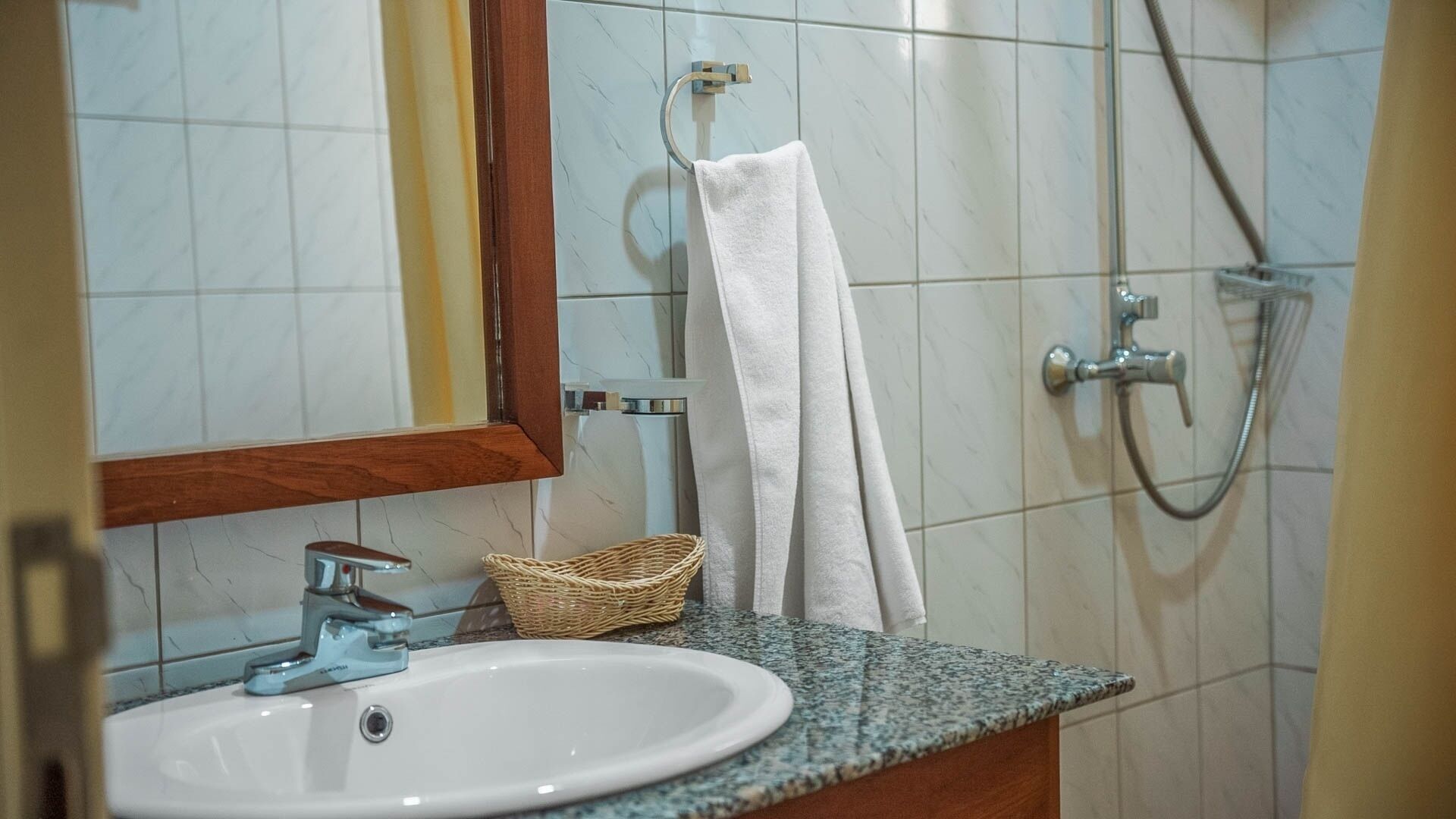 A bathroom with a sink, a mirror, a towel rack, and a shower.