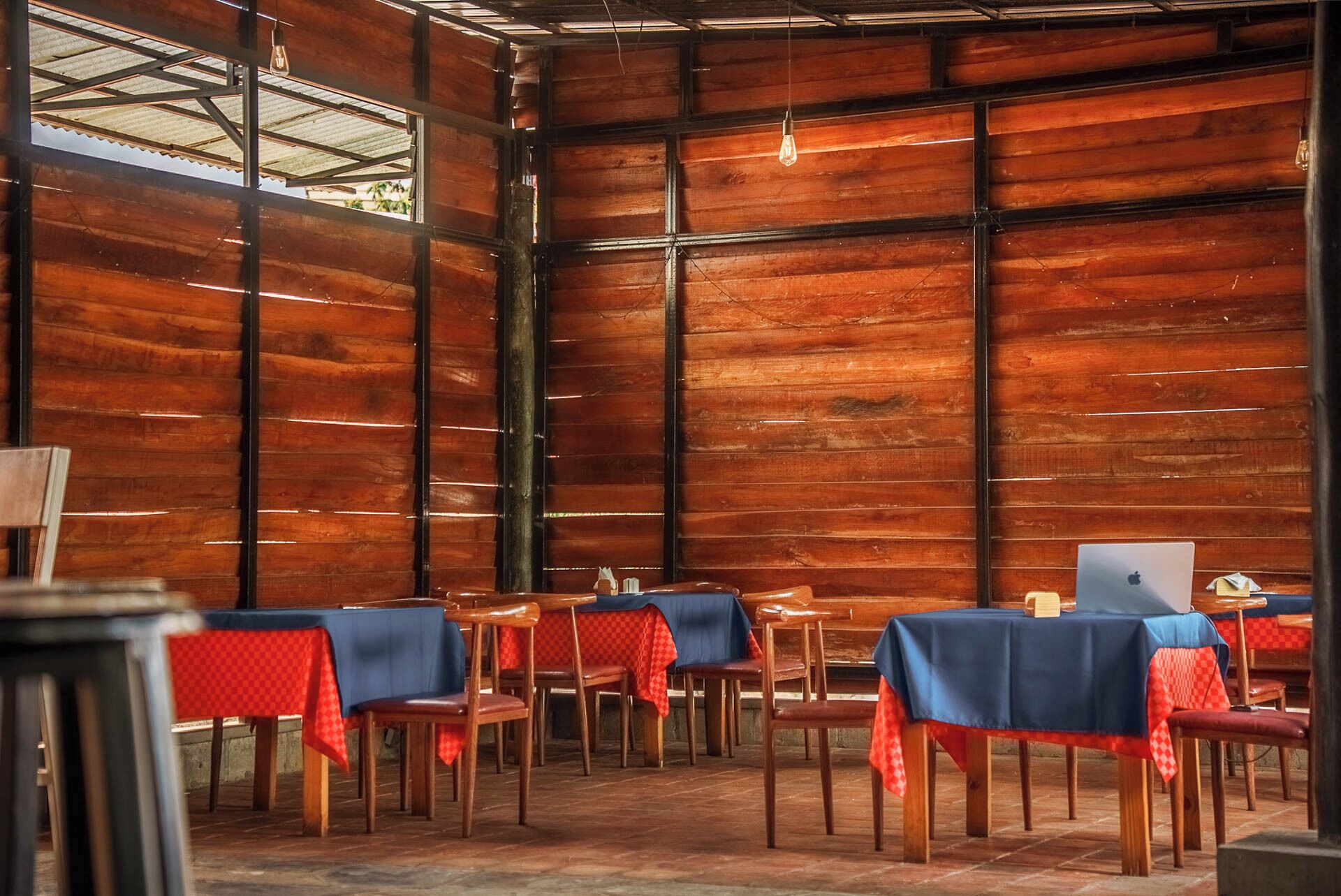 Un comedor interior con paredes de madera y mesas cubiertas con manteles a cuadros rojos y azules.