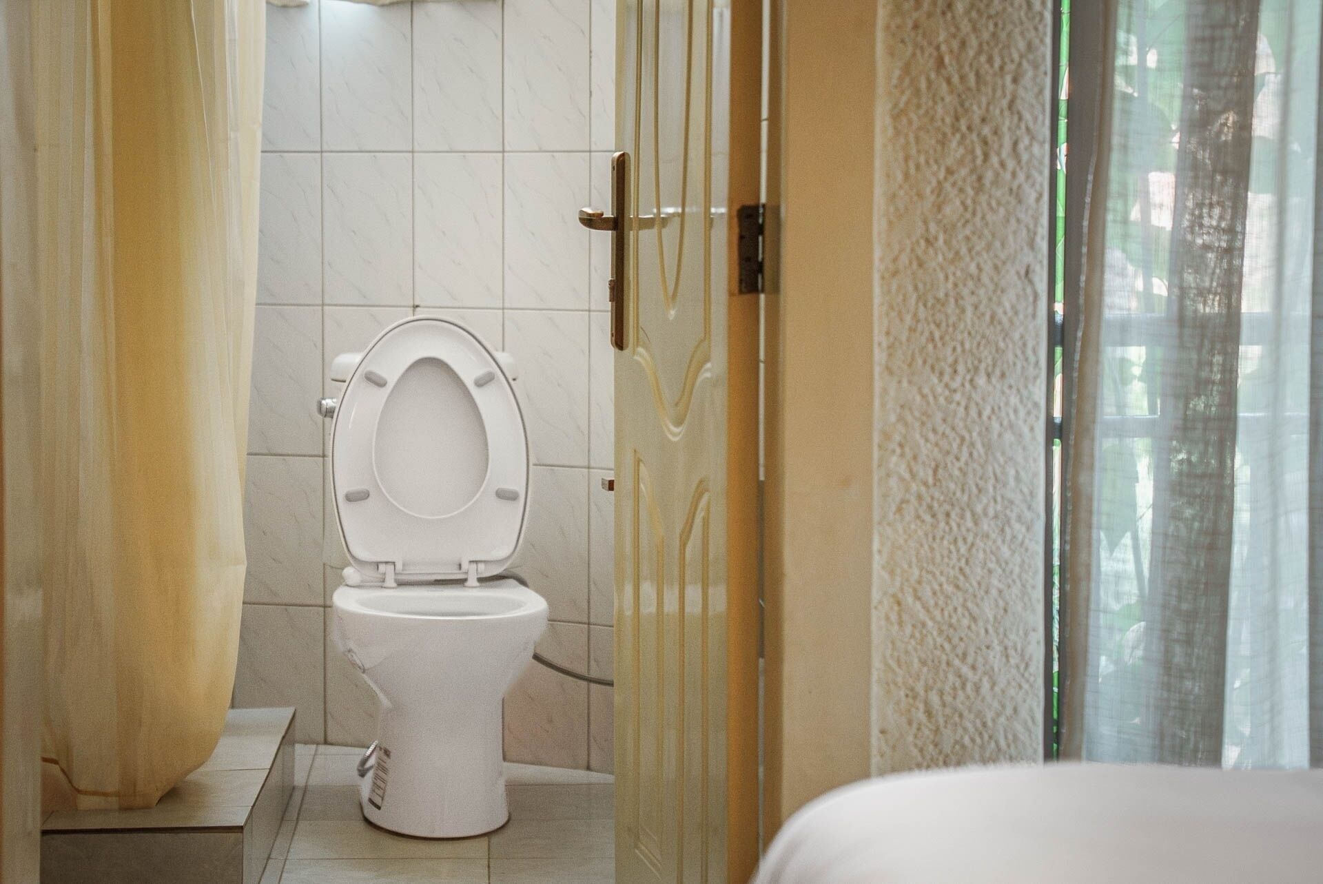 A bathroom with a white toilet, tiled walls, and a glass shower enclosure.