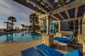 Zona de piscina con sillones de descanso, una pérgola y vistas al océano.
