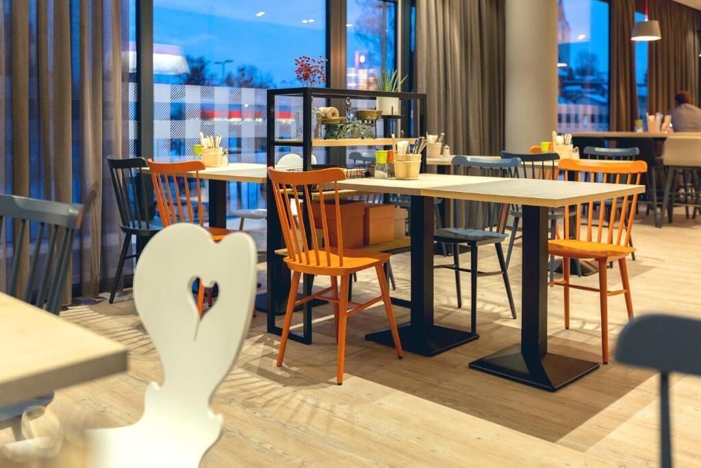 Een restaurantinterieur met houten vloeren, oranje stoelen en tafels.