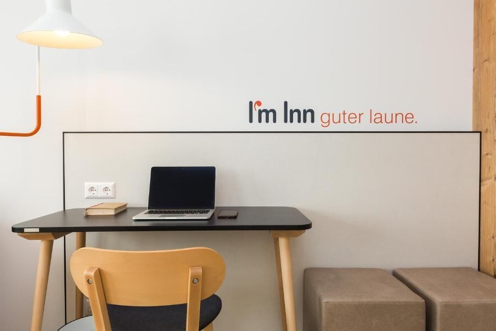 Een moderne werkplek met een laptop op een zwart bureau, een stoel en een wandlamp.