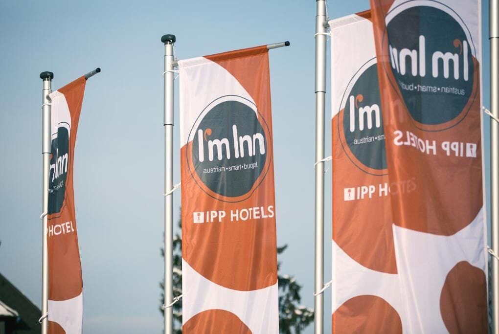 Tres banderas de 'I Inn' y 'IPP Hotels' con un logotipo que presenta una 'I' estilizada y el texto 'hotel inteligente austríaco'.