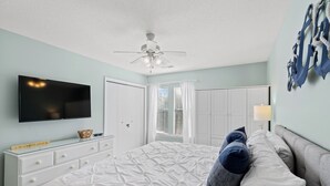 Une chambre à coucher comprenant un lit, un téléviseur, un ventilateur de plafond et une armoire.