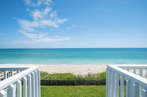 A beach view from a deck with white railings, clear blue sky, and calm sea. - Spacious Beachfront Pool Home in charming Melbourne Beach (Melbourne Beach)
