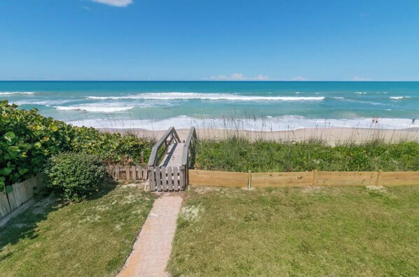 A pathway leading to a beach with a wooden fence and a wooden boardwalk. - Spacious Beachfront Pool Home in charming Melbourne Beach (Melbourne Beach)