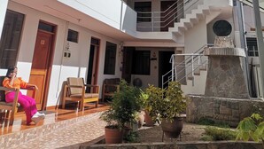 Ένα πολυώροφο κτίριο με μια κεντρική σκάλα, έναν εξωτερικό χώρο με καθίσματα και γλάστρες με φυτά.