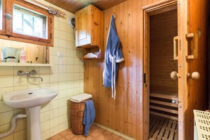 A wooden bathroom with a sink, a towel rack, and a shower door.