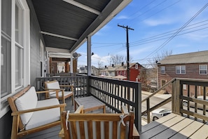 Une terrasse en bois avec des sièges extérieurs et une vue sur les bâtiments voisins.
