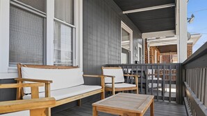 Eine Holzterrasse mit einer Couch, Stühlen, einem Tisch und einem Geländer.