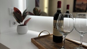 A wine bottle and two glasses on a wooden tray on a white countertop. - Suites Pantheon Rome - 3 (Roma)