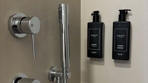 A bathroom with a modern shower system, two black shower bottles labeled 'CULTI MILANO', and a wall-mounted towel rack. - Suites Pantheon Rome - 3 (Roma)