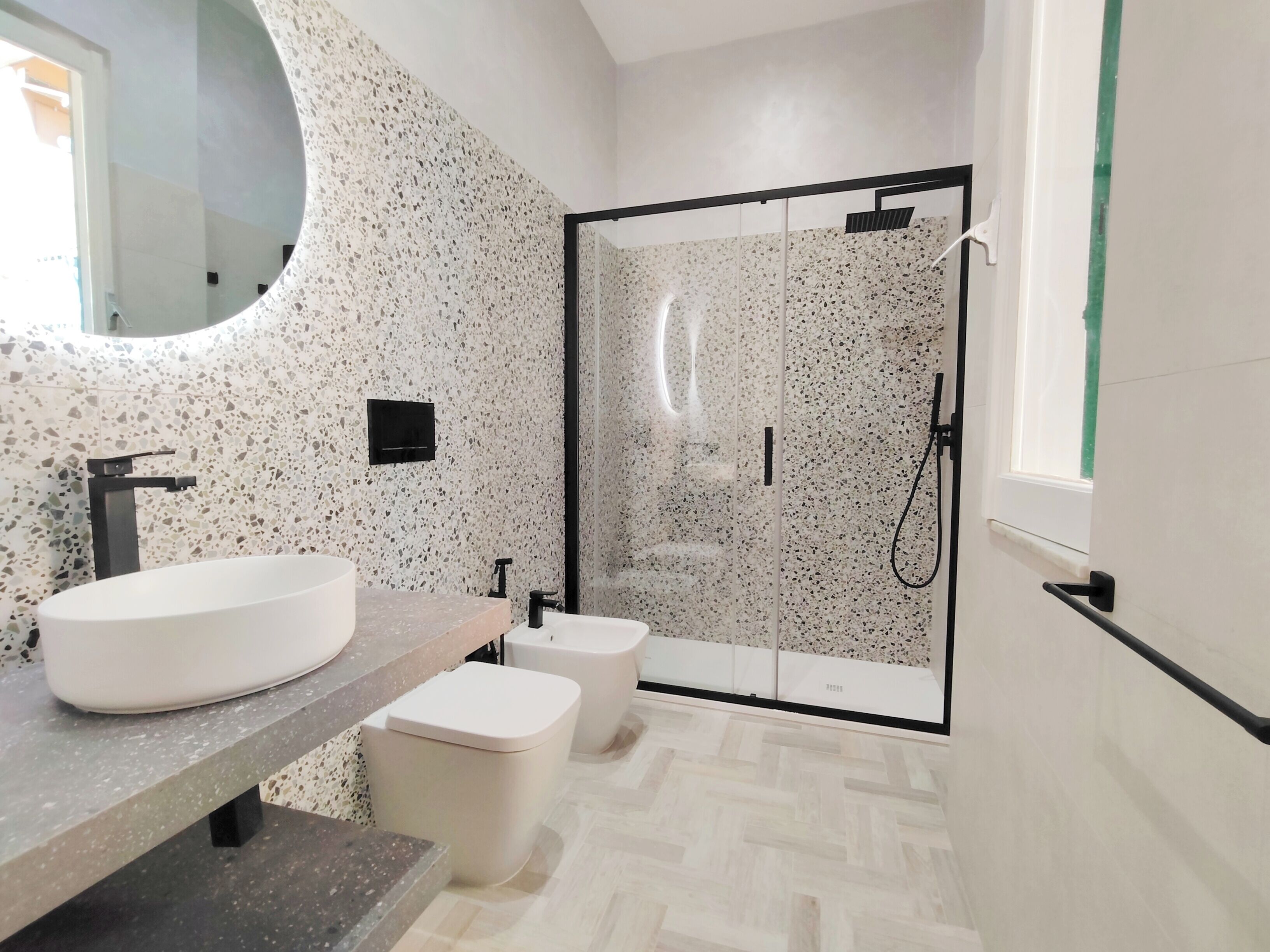 A modern bathroom with a freestanding sink, a toilet, and a glass-enclosed shower area.