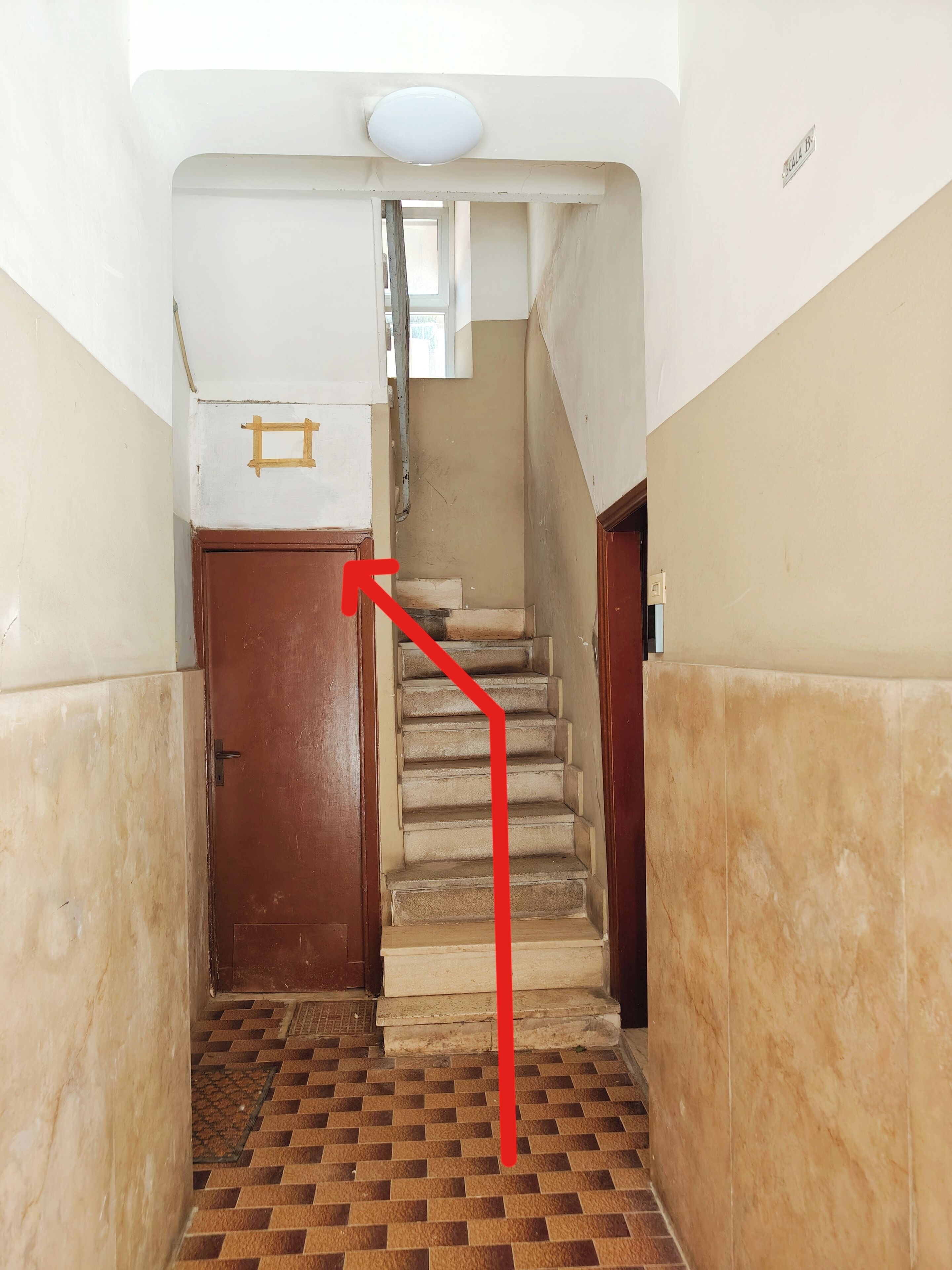 Un couloir étroit avec un escalier menant à un palier.