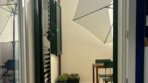 Un espace extérieur aménagé en patio, avec un sol carrelé, une petite table, des chaises et des plantes en pot.