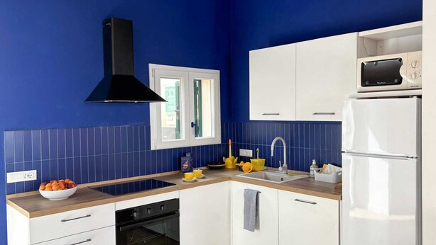 Une cuisine moderne avec des armoires blanches, une cuisinière noire et un four encastré.
