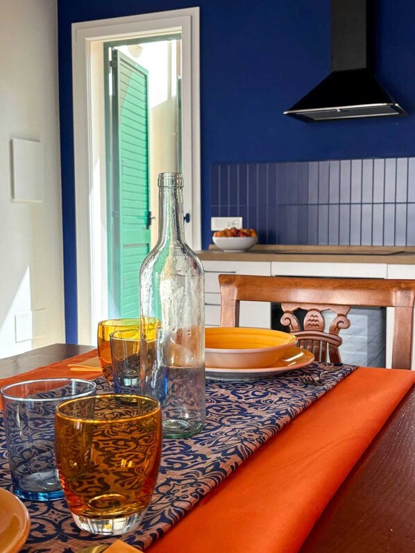 A dining table with a patterned tablecloth, a bottle, and glasses. - Casa Giù, a renovated apartment near the sea and the heart of Tuscany! (Cecina)