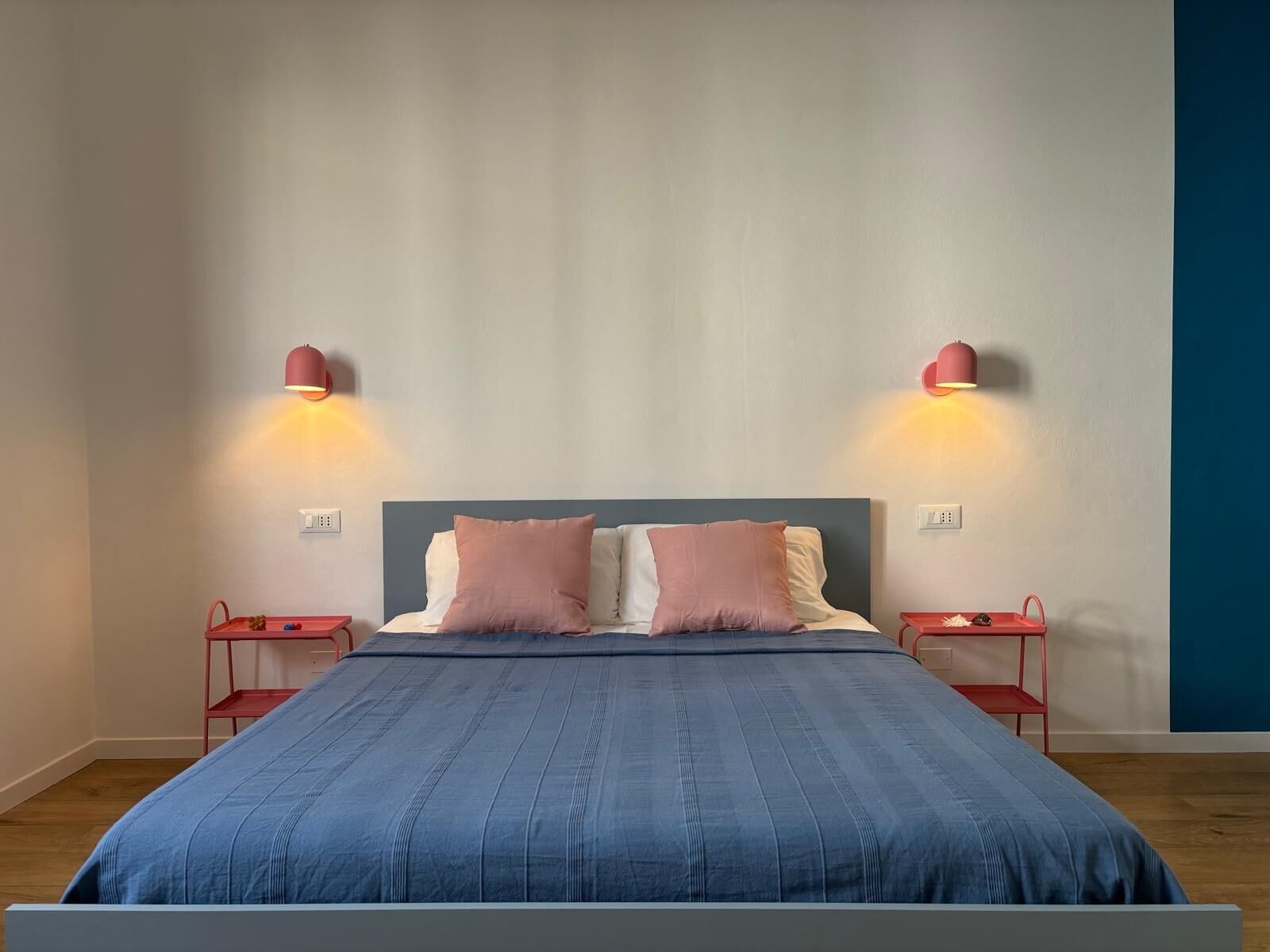A bedroom with a bed, two bedside tables, and two wall-mounted lamps.