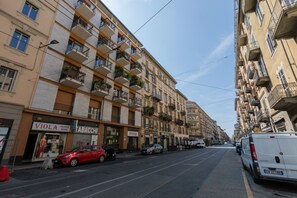 Eine Straße mit mehrstöckigen Gebäuden, ein rotes Auto parkte am Straßenrand und ein weißer Lieferwagen.