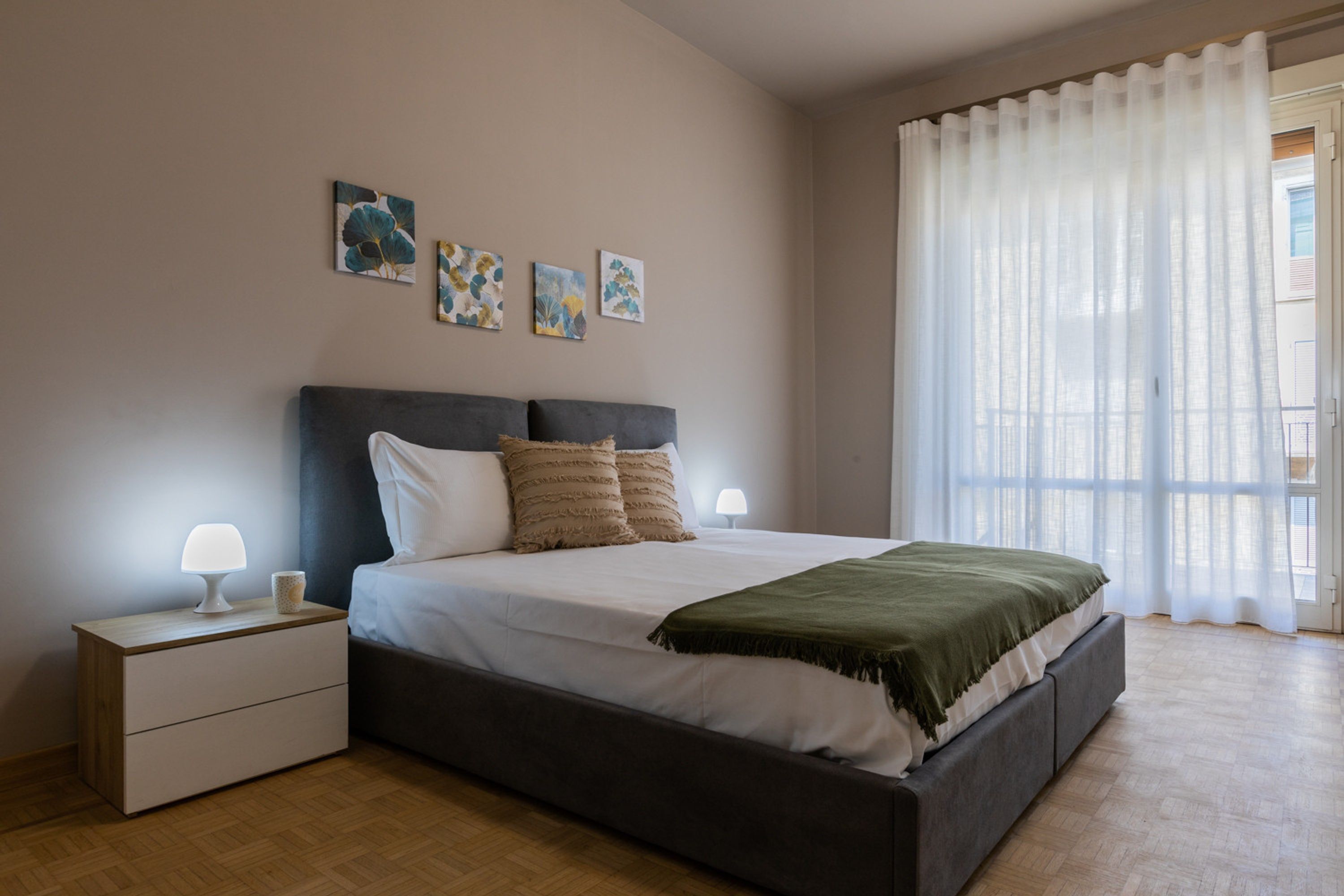 Une chambre à coucher avec un lit, des tables de chevet et des œuvres d’art accrochées au mur.