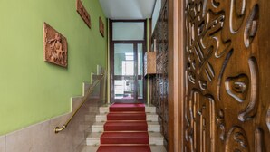 A staircase with a red carpet leading to a door with intricate woodwork. - Casa Fiore by Wonderful Italy (Turin)