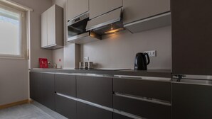 A modern kitchen with dark cabinetry, stainless steel appliances, and a window providing natural light. - Casa Fiore by Wonderful Italy (Turin)