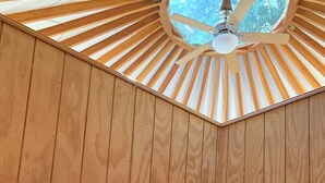A room with a sloped ceiling, wooden walls, a bed with dark bedding, and a single bedside lamp. - Canyon Creek Resort (Winters)