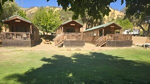 A campground with three wooden cabins, each with a balcony and a small deck. - Canyon Creek Resort (Winters)