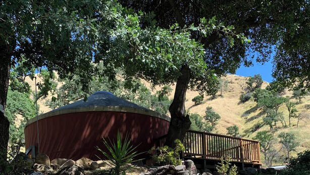A garden with a wooden deck, a red structure, and a variety of plants and rocks. - Canyon Creek Resort (Winters)