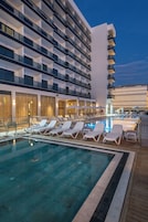 Una piscina al aire libre, sombrillas, sillones reclinables de piscina