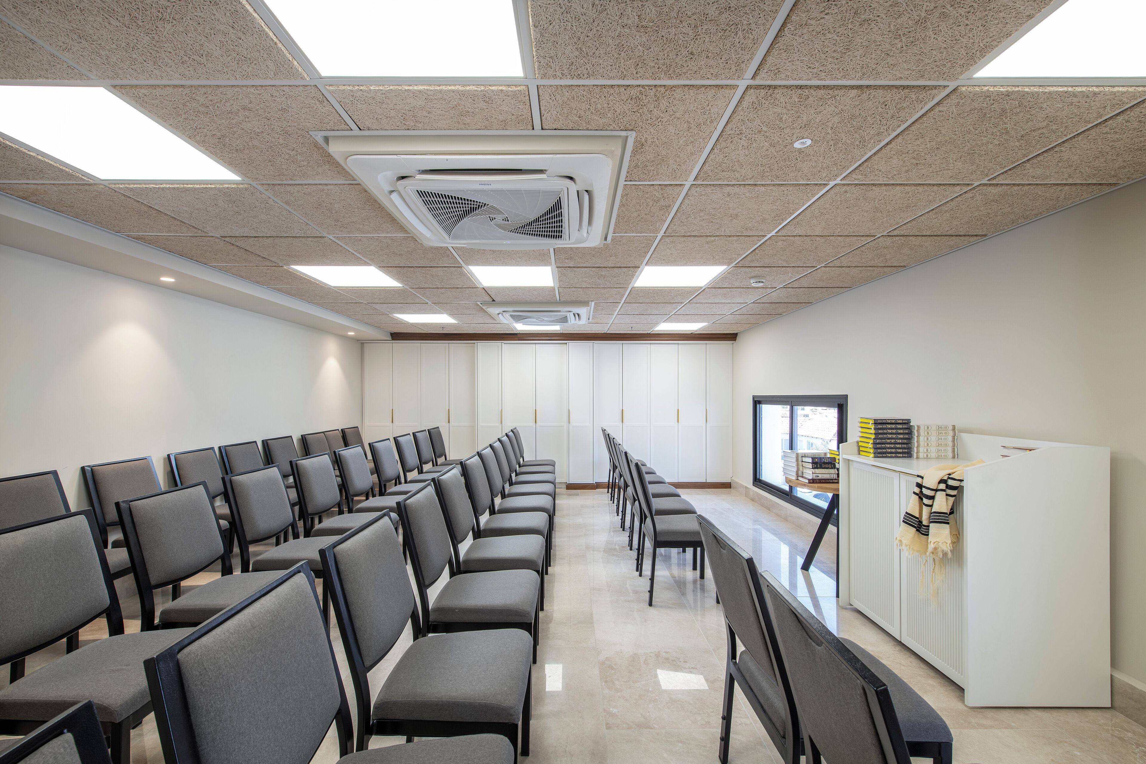 Uma sala de conferências com fileiras de cadeiras, um púlpito e uma lousa.