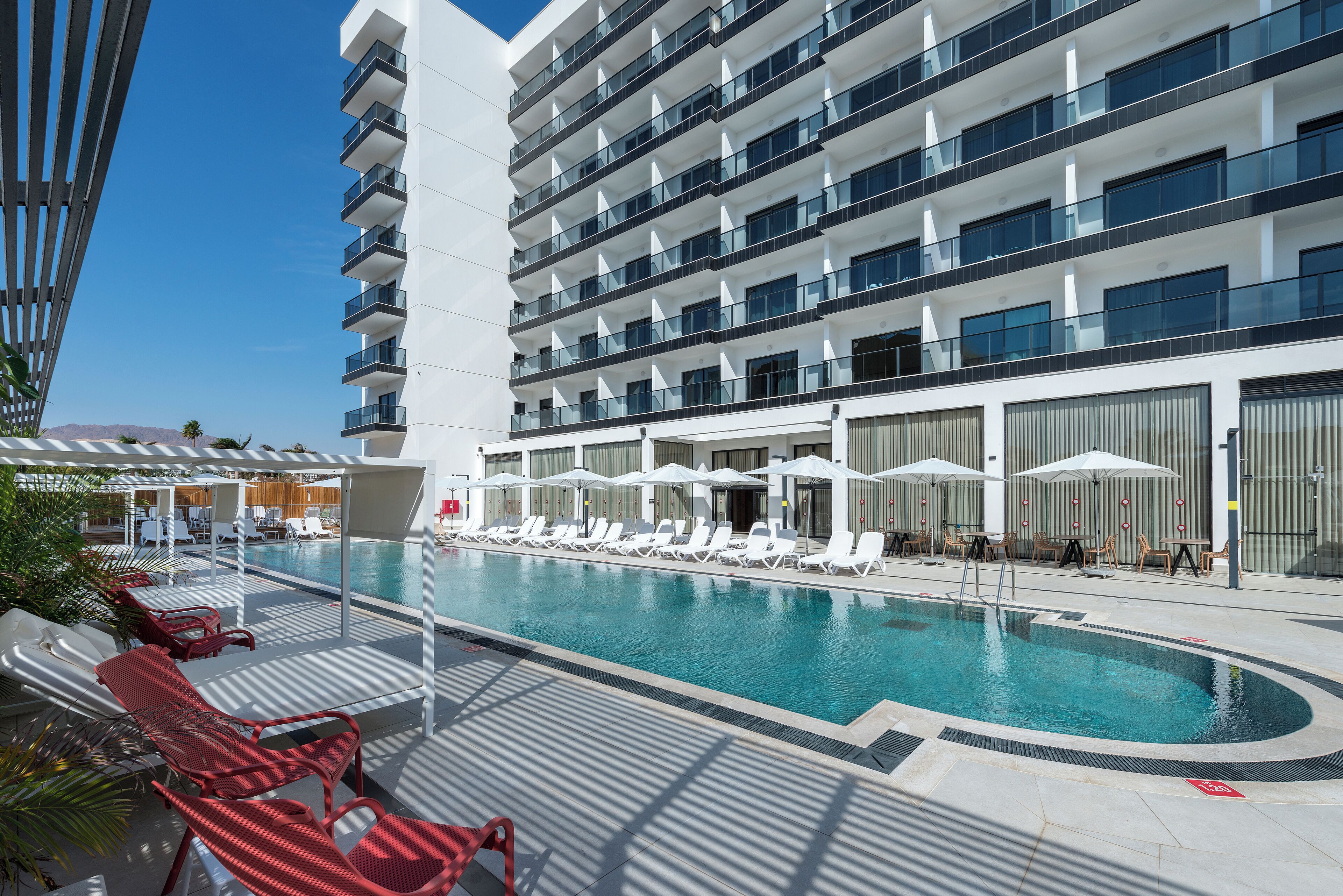 Una piscina al aire libre, sombrillas, sillones reclinables de piscina