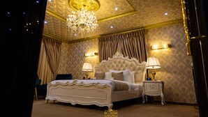 Un dormitorio lujoso con una cama grande, un techo ornamentado y una decoración elegante.