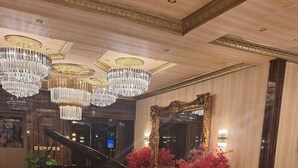 Un lobby espacioso con un piano de cola, candelabros ornamentales y un espejo grande.
