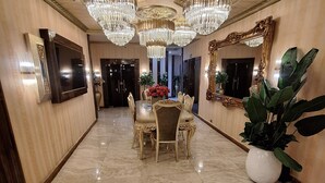 Un vestíbulo amplio con piso de mármol, candelabros elegantes, un espejo grande y un televisor en la pared.