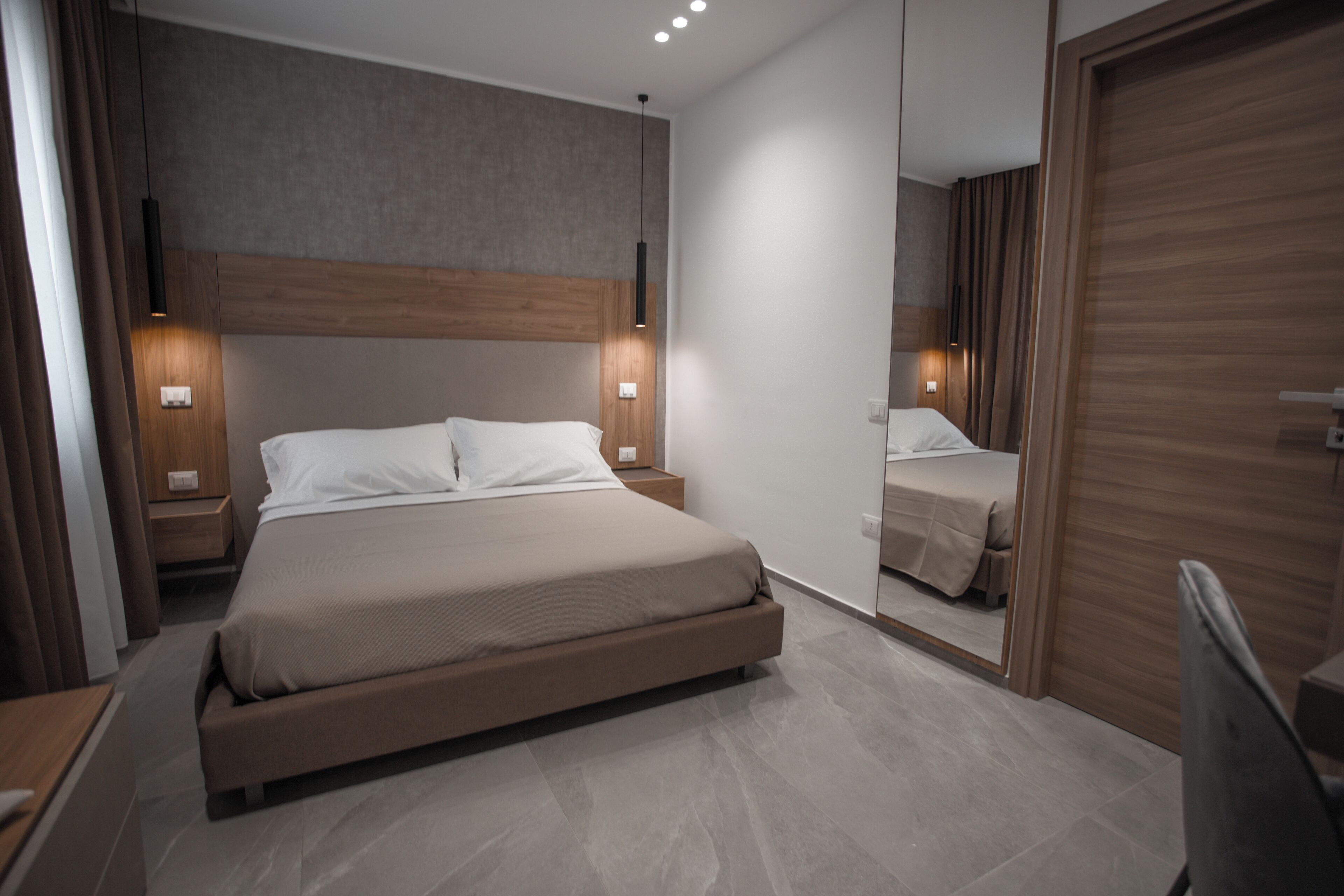 Une chambre à coucher moderne avec un grand lit, des tables de chevet et un miroir.