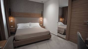 Une chambre à coucher moderne avec un grand lit, des tables de chevet et un miroir.
