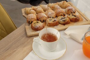 Uma mesa de madeira com uma bandeja de doces e uma chávena de chá.